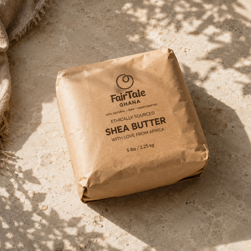 A 5 lb brown paper bag of FairTale Ghana Shea Butter, photographed from an overhead angle on a textured beige stone surface with dappled sunlight and shadows.