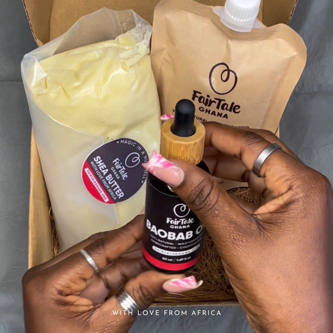 Hands holding a FairTale GHANA Shea butter pouch and Baobab oil bottle inside an opened gift box